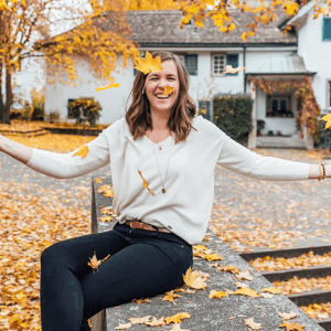 A self-care celebration: woman throwing leaves in the air while seated on a bench.